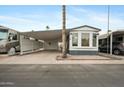 Mobile home exterior with carport, landscaping, and palm trees at 977 S Oxide Dr # 977, Apache Junction, AZ 85119