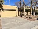 View of a two-car garage with a driveway and mature palm trees at 1424 E Kerry Ln, Phoenix, AZ 85024