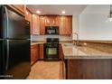 Kitchen features dark wood cabinets, granite counters, and black appliances at 5450 E Deer Valley Dr # 4201, Phoenix, AZ 85054