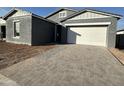 Gray exterior house with white garage door and a brick paved driveway at 11446 E Utah Ave, Mesa, AZ 85212