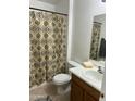 Bathroom with shower/tub combo, wood vanity, and patterned curtain at 15350 W Mauna Loa Ln, Surprise, AZ 85379