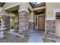 Front entrance with stone columns and a wooden door at 15526 W Minnezona Ave, Goodyear, AZ 85395