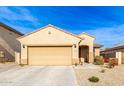 Tan house with a two-car garage and desert landscaping at 17662 W Daley Ln, Surprise, AZ 85387