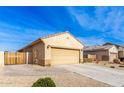 Tan house with a two-car garage and a wooden gate at 17662 W Daley Ln, Surprise, AZ 85387