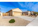 Tan house with a two-car garage and a wooden gate at 17662 W Daley Ln, Surprise, AZ 85387