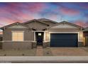 Charming single-story home with a brick driveway, desert landscaping and a dark blue garage door at 4727 N 177Th Dr, Goodyear, AZ 85395