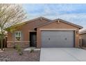 Brown house with gray garage door and stone accents at 6843 W Samantha Way, Laveen, AZ 85339