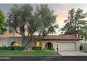 Single-story home with a red tile roof and arched entryways, nestled on a landscaped lot at 7301 E Claremont St, Scottsdale, AZ 85250