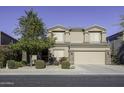 Two-story house with tan exterior, landscaped yard, and two-car garage at 1240 W Falls Canyon Dr, Casa Grande, AZ 85122