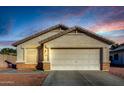 Tan house with a two-car garage and landscaping; sunset in the background at 12962 W Catalina Dr, Avondale, AZ 85392