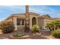 Front view of a tan house with arched entryway and mature landscaping at 18109 W Skyline Dr, Surprise, AZ 85374