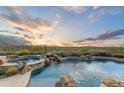 Expansive pool and spa with a waterfall feature and breathtaking mountain views at 9697 E Preserve Way, Scottsdale, AZ 85262