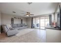 Living room with gray sectional sofa, backyard access, and ceiling fan at 29362 W Weldon Ave, Buckeye, AZ 85396