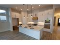 Modern kitchen with white cabinets, a large center island, stainless steel appliances, and tile floors at 32496 N 135Th Dr, Peoria, AZ 85383