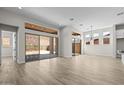 Bright and spacious living room featuring wood-look tile flooring and sliding glass doors to the patio at 32496 N 135Th Dr, Peoria, AZ 85383