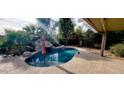 Kidney-shaped pool with a rock waterfall feature and covered patio at 13383 W Ironwood St, Surprise, AZ 85374