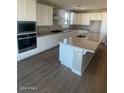 Modern kitchen featuring white cabinetry, granite island, and hardwood floors at 19026 W Stella Ave, Waddell, AZ 85355