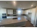 Spacious kitchen with an island, white cabinets, and granite countertops at 19026 W Stella Ave, Waddell, AZ 85355