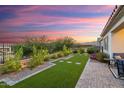 Beautiful backyard with artificial turf, manicured landscaping, a fence, and a stunning sunset backdrop at 20363 W Coolidge St, Buckeye, AZ 85396