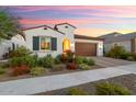 Charming single-story home with a well-maintained front yard, flowering plants, a brown garage door, and a terracotta roof at 20363 W Coolidge St, Buckeye, AZ 85396