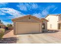 Tan house with a two-car garage and desert landscaping at 7244 S Sunrise Way, Buckeye, AZ 85326