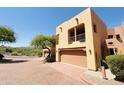 View of a two-story stucco home with a two-car garage, desert landscaping, and mountain views at 13227 N Mimosa Dr # 117, Fountain Hills, AZ 85268