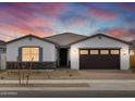 Charming single-story home featuring a two-car garage with sunset sky overhead at 17691 W Southgate Ave, Goodyear, AZ 85338