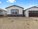 Single story home exterior with white stucco, stone accents, and desert landscaping at 17691 W Southgate Ave, Goodyear, AZ 85338