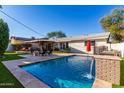 Relaxing pool area with a brick water feature and patio furniture at 7529 E Windsor Ave, Scottsdale, AZ 85257