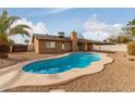 Kidney shaped swimming pool in backyard with tan colored decking at 7202 W Carol Ave, Peoria, AZ 85345