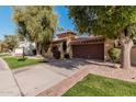 Tan stucco house with brown garage door and nicely landscaped yard at 10473 N 87Th Pl, Scottsdale, AZ 85258