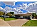 A well-maintained single-story house with a brick driveway, lush lawn, and modern garage door at 615 E Winter Dr, Phoenix, AZ 85020