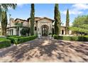 Stately home with a circular brick driveway, manicured hedges, and an arched entryway with black iron doors at 6800 E Caballo Dr, Paradise Valley, AZ 85253