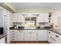 Kitchen with white cabinets, a large window and dark countertops at 10012 W Sandstone Dr, Sun City, AZ 85351