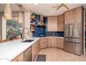 Modern kitchen with wood cabinets, white countertops, and blue tile backsplash at 19941 N Summer Dream Dr, Surprise, AZ 85374