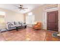 Bright living room with tiled floors, gray sofa, and orange accent chair at 3531 E Utopia Rd, Phoenix, AZ 85050