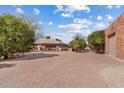 Wide concrete brick driveway leading to a charming home with mature trees and detached garage at 4024 E Hermosa Vista Dr, Mesa, AZ 85215