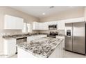 Modern kitchen with white cabinets, granite countertops, and stainless steel appliances at 414 E Eason Ave, Buckeye, AZ 85326