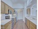 Bright kitchen boasts stainless steel appliances, wooden cabinets, and laminate floors at 11517 W Coral Snake Ct, Surprise, AZ 85378