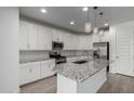 Modern kitchen features stainless appliances, white cabinets, tile backsplash, granite countertops, and pendant lighting above island at 9658 E Tahoe Cir, Mesa, AZ 85212