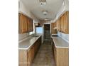 Long galley kitchen with wood cabinets and tile flooring at 10546 W Catalina Dr, Arizona City, AZ 85123