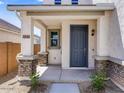 Charming front porch with stone-base columns and a stylish blue front door at 14644 W Sand Hills Rd, Surprise, AZ 85387