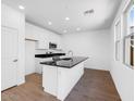 Bright kitchen with white cabinets, granite counters, a kitchen island, and wood-look floors at 14644 W Sand Hills Rd, Surprise, AZ 85387