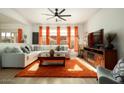 Bright living room with L-shaped sofa, orange rug, and a fireplace at 15437 W Domingo Ln, Sun City West, AZ 85375