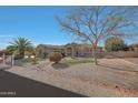 Beautiful single-story home with desert landscaping, mature trees, and a well-manicured lawn at 18009 W Denton Ave, Litchfield Park, AZ 85340