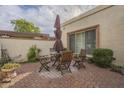 Brick patio with wooden table and chairs, umbrella, and shrubs at 2911 W Lamar Rd, Phoenix, AZ 85017