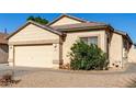 Tan house with a two-car garage and mature shrubs at 5810 W Puget Ave, Glendale, AZ 85302