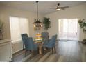 Charming dining area with a glass-top table and four blue chairs, near sliding doors at 12221 N 122 Dr, El Mirage, AZ 85335