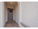 Gray front door with wreath, brick flooring, and stucco wall at 22413 N 101St Ave, Peoria, AZ 85383