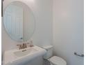 Small half bathroom with white sink, toilet, and oval mirror at 22413 N 101St Ave, Peoria, AZ 85383